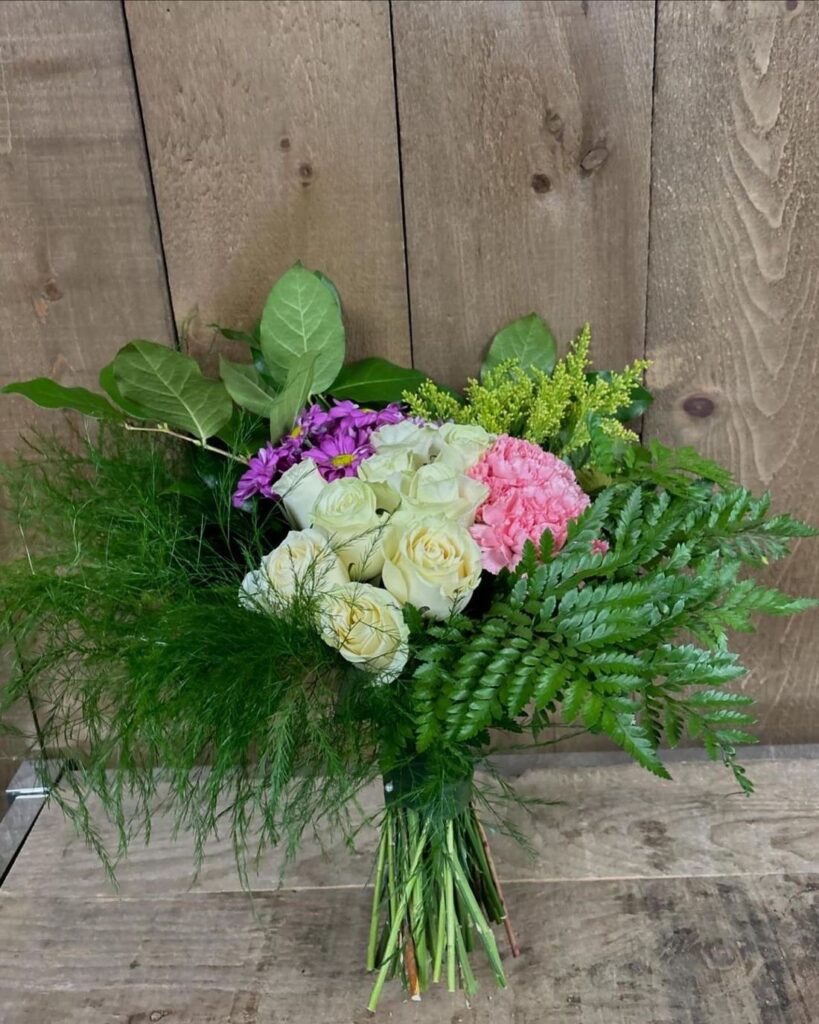 Hand-tied bouquet of ivory roses and a pink carnation