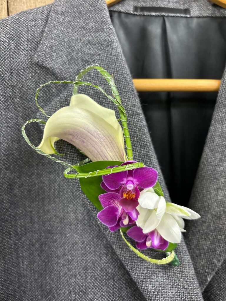 Boutonnière of a blush calla lily with magenta mini orchids
