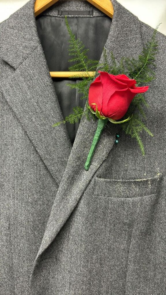 Red rose boutonnière with feathery asparagus fern and pearl pins