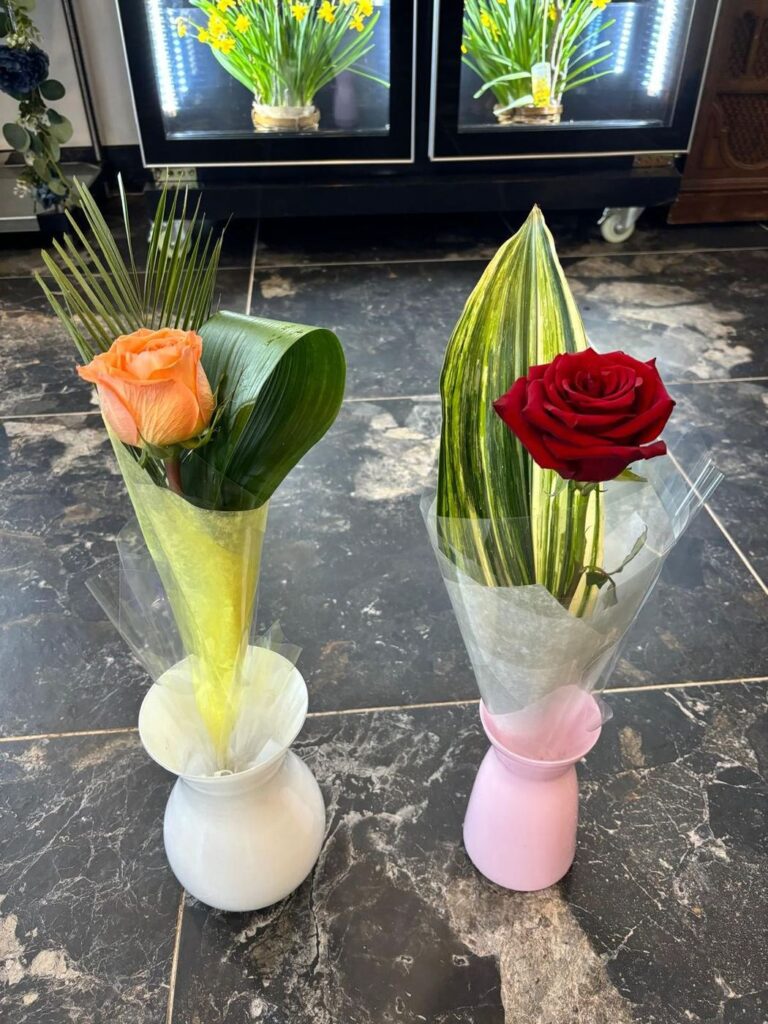 Single red and peach roses in small pastel vases