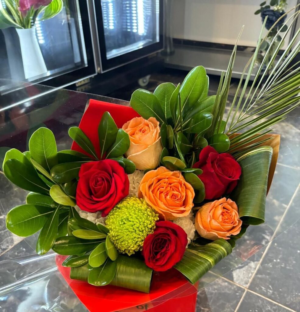 Red and peach roses wrapped in glossy leaves